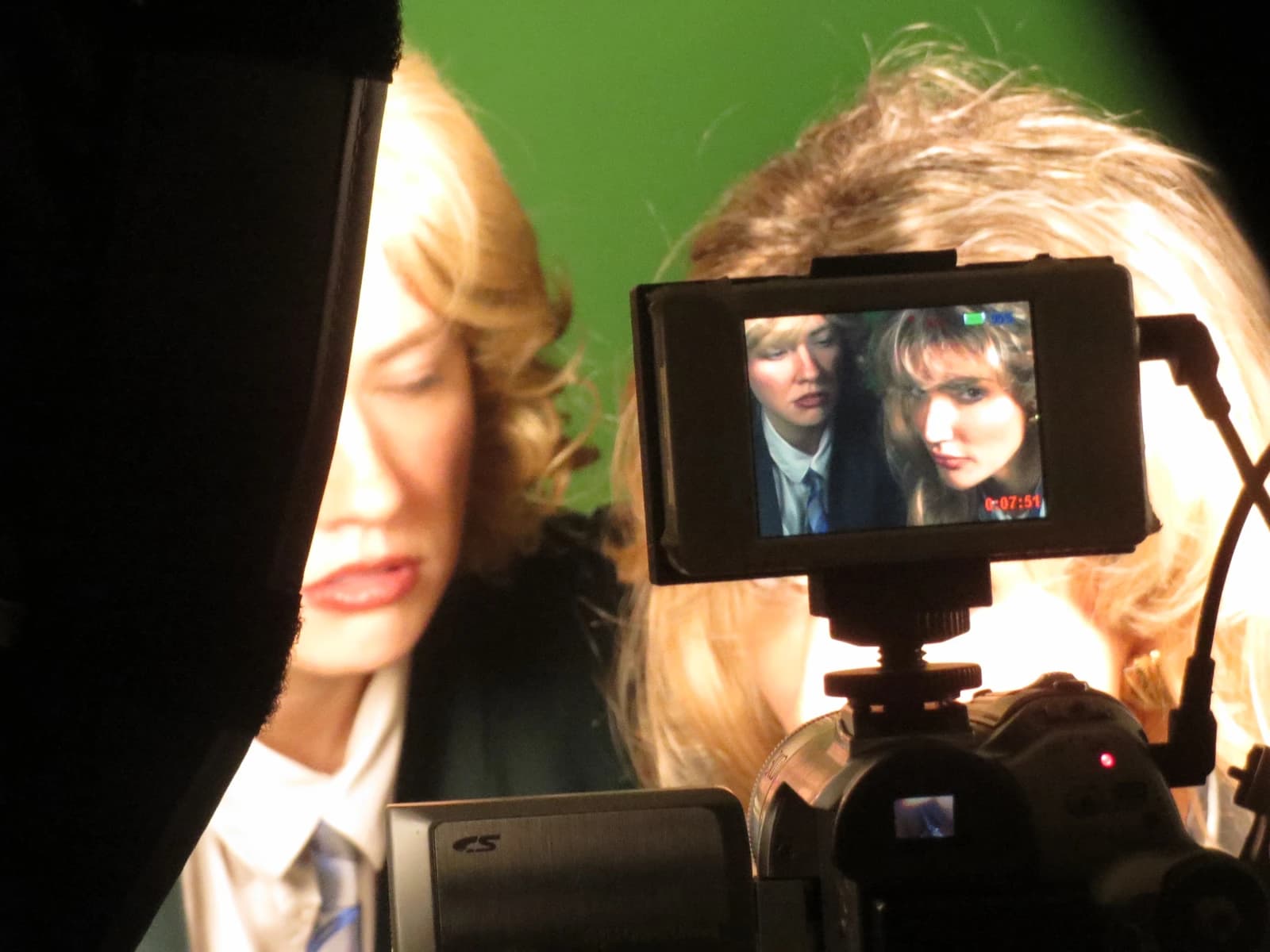 The two news anchors framed in the camera monitor behind the scenes